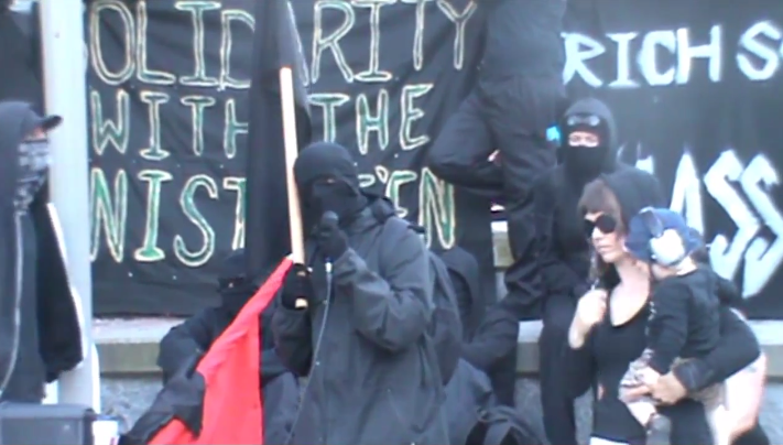 Masked Black Bloc anarchists give a speech at the cenotaph 