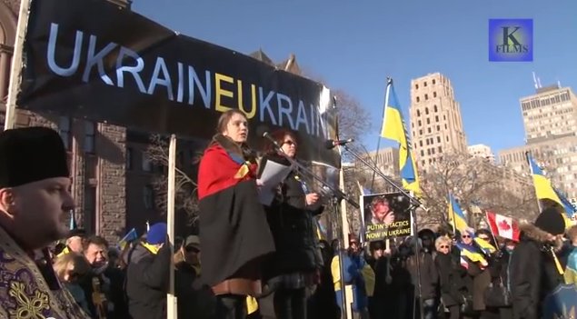 Ukrainian Insurgent Army flag draped over a protester in Queen's Park
