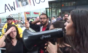 Sammy Yatim's relative pleads to the crowd asking them to behave while Syed Hussan tries to hijack her march